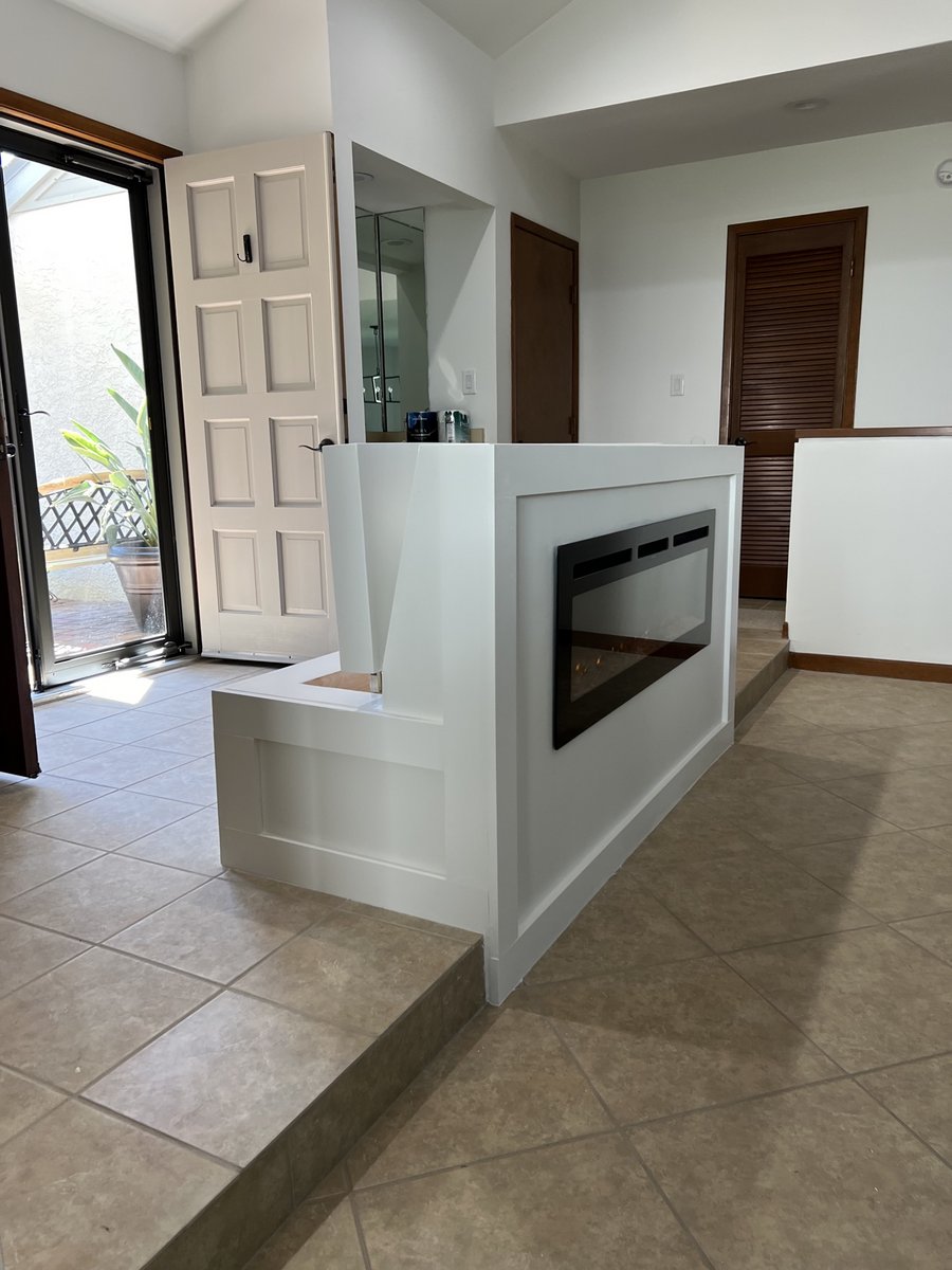 Custom white fireplace half-wall with electric fireplace insert built by KM
